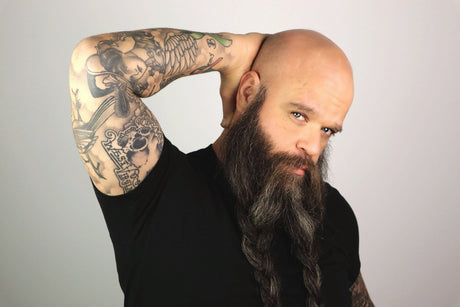 A man with a long beard and tattoos, showcasing his natural radiance using Mountaineer Brand Products&#39; Bald Head Shine Away (PH Balancing Toner).