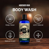 Bottle of Mountaineer Brand Products Natural Men's Body Wash labeled "timber" on a wooden surface with icons indicating it is deep clean, 100% natural, has a natural scent, and is