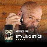 A man is effortlessly styling his beard with a Mountaineer Brand Products Styling Stick - 9 Scents Available, free from harmful chemicals.